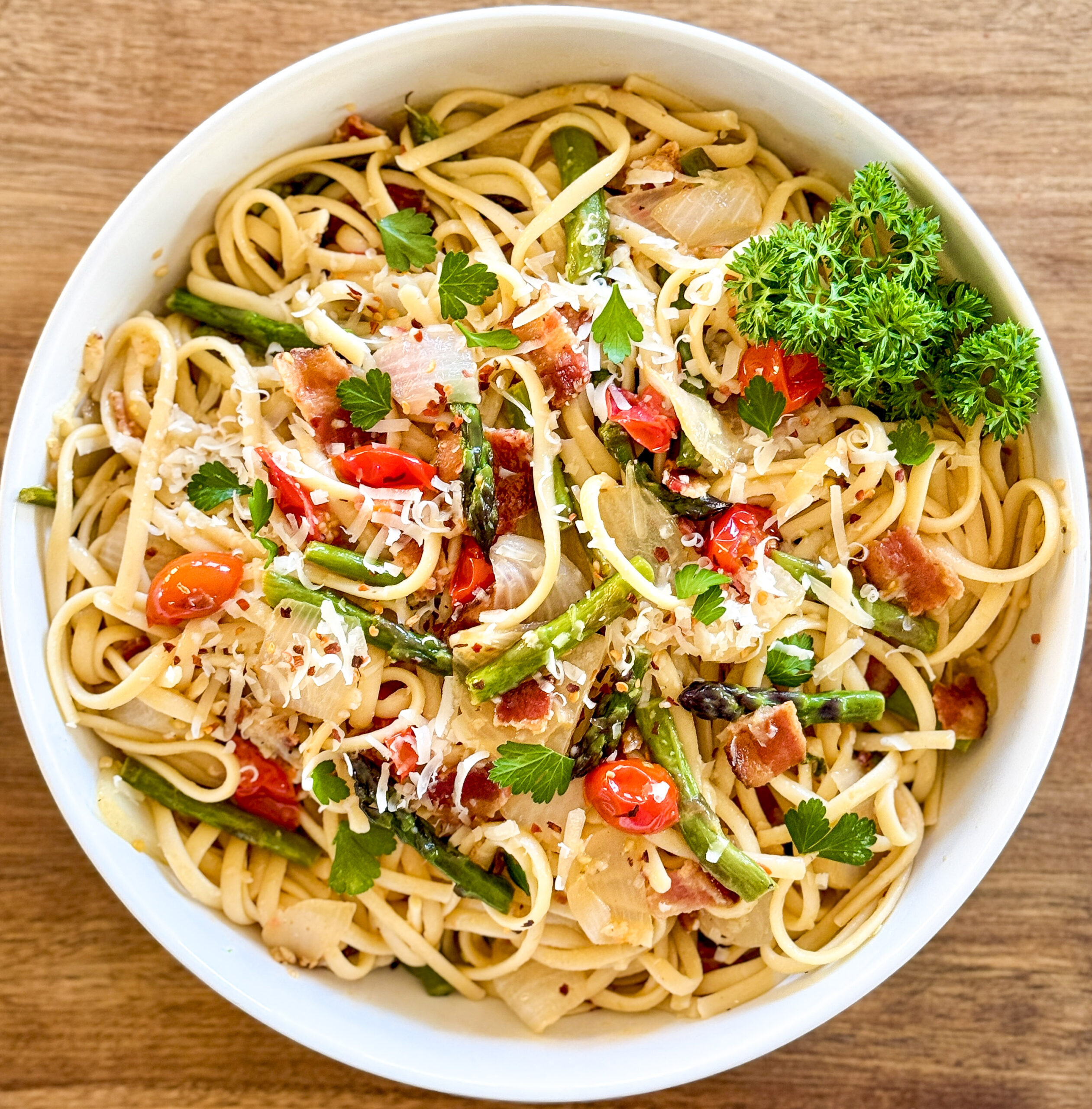 white bowl of pasta, vegetables, and cheese sitting on a brown table